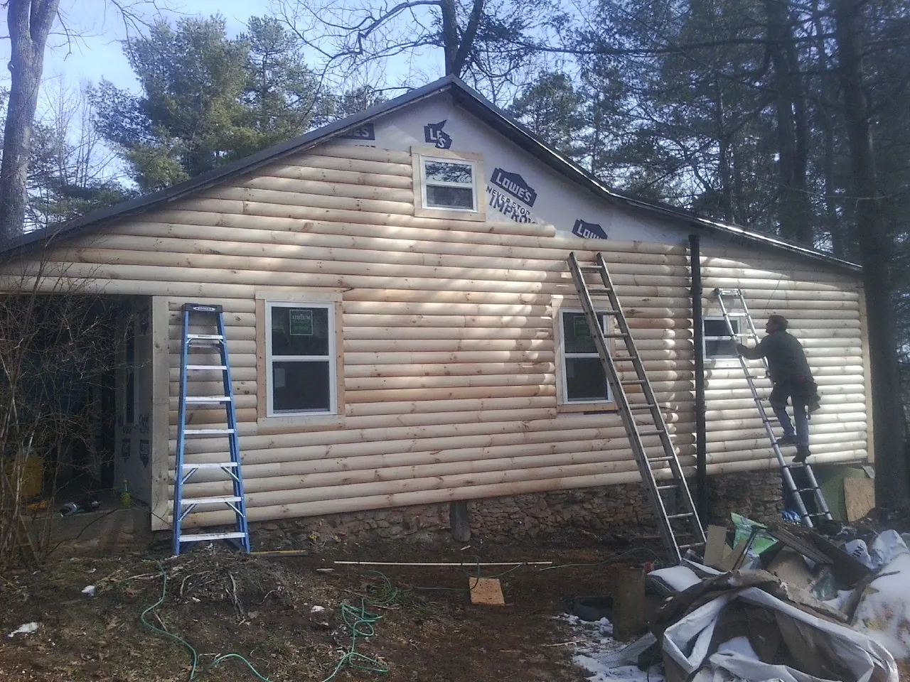 Ladders set against fresh log siding during an exterior remodel in Rowan