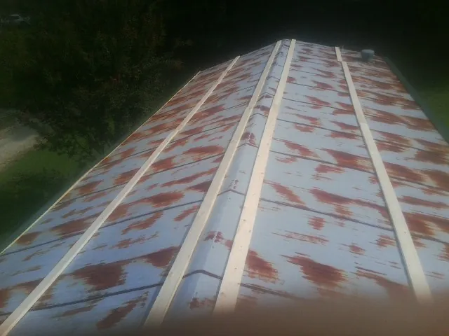 Rusted metal roof panels with new wood purlins before replacement — Storm Damage Roof Repair in Rowan by Roofing Brothers