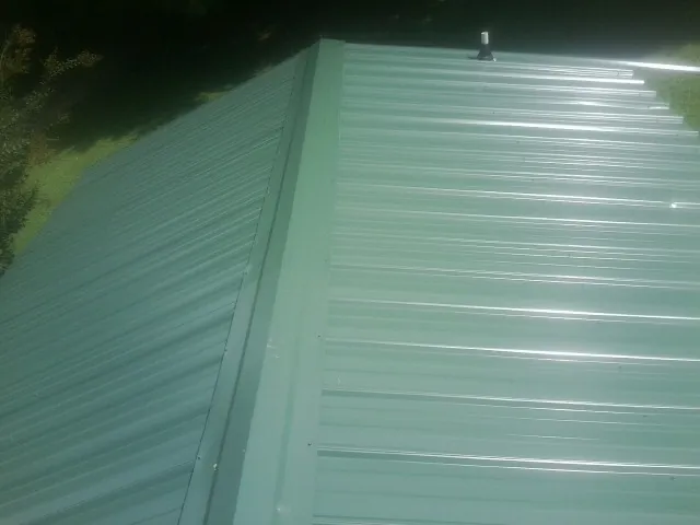 New green metal panels meeting at the ridge of a roof — Flat Roof Repair work by our crew in Rowan