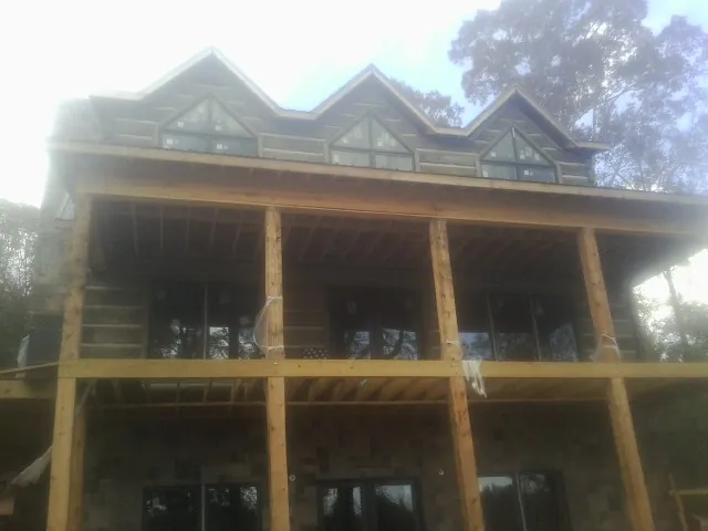 Dormers and porch framing on a large log home under construction — Roof Coating work by our crew in Rowan