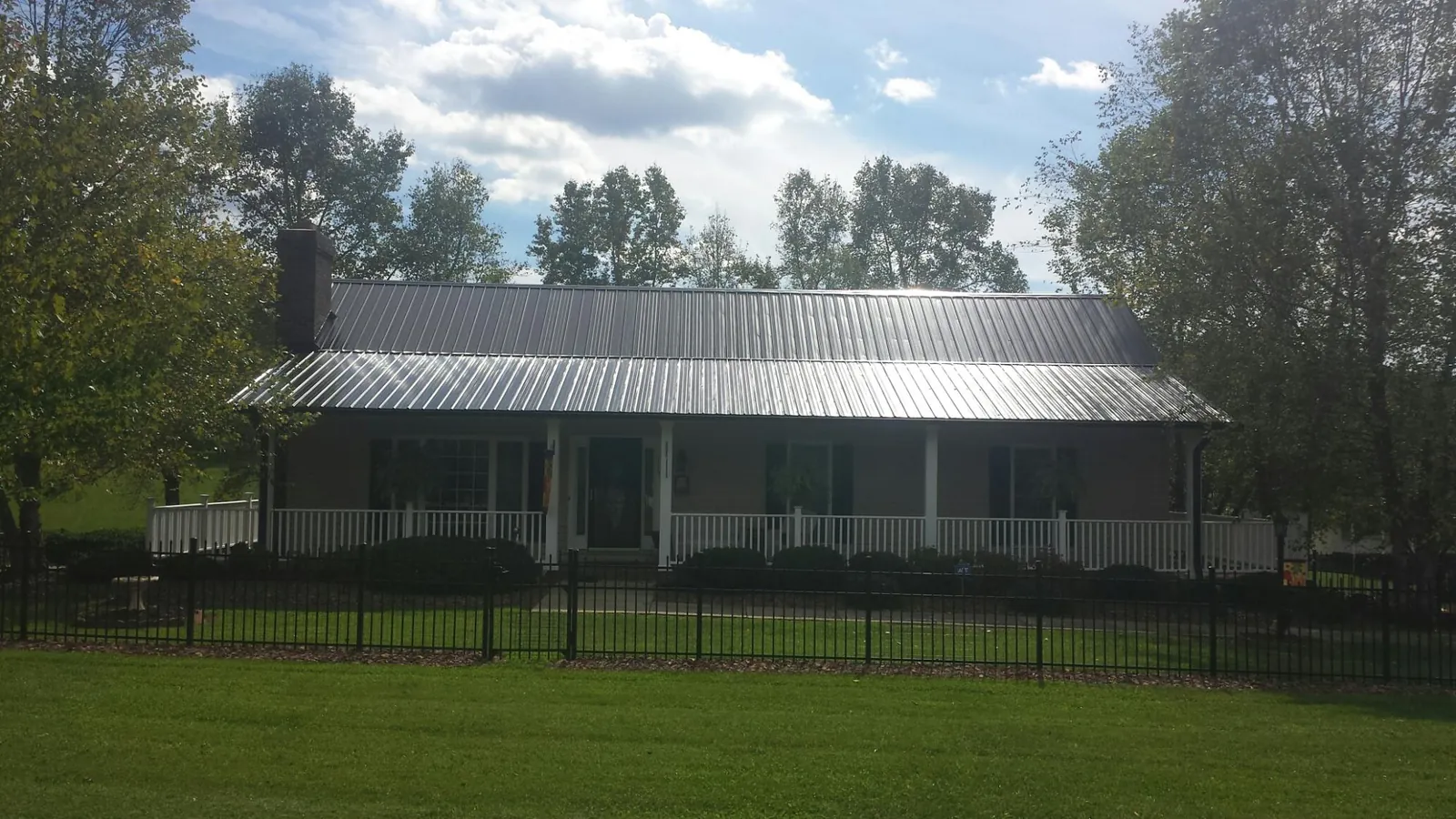 Gray metal roof on a brick ranch with a full width front porch — Gutter Guard Installation work by our crew in Rowan