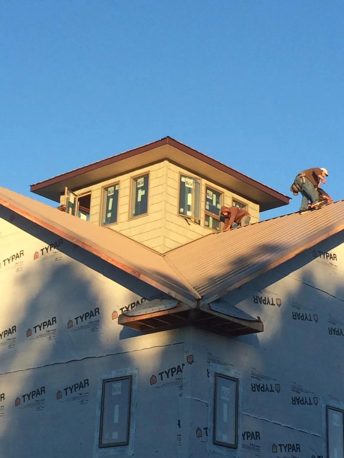 Roofers working around a rooftop cupola on a new metal roof at sunset — Roof Waterproofing in Rowan by Roofing Brothers